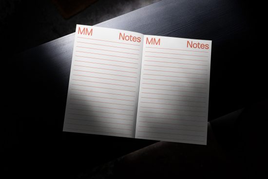 Open notebook mockup on dark surface, displaying lined pages with red header, ideal for stationery design presentation.