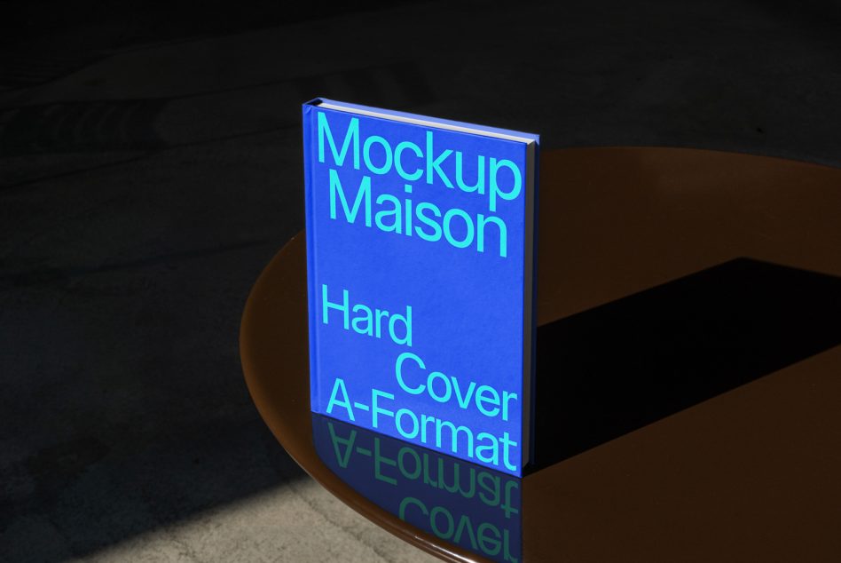 Cyan glowing text on blue hardcover book mockup with reflection on dark surface