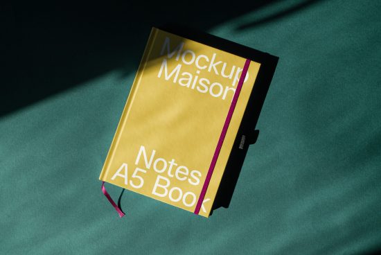 Yellow A5 notebook mockup with shadow overlay on dark green background, perfect for showcasing font and graphic designs.