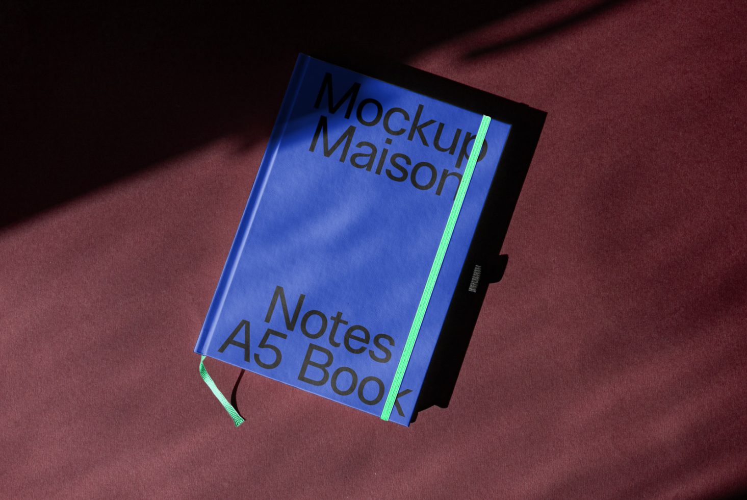 Blue notebook mockup with green bookmark on maroon background, A5 book design template, realistic shadow overlay, graphic assets for designers.