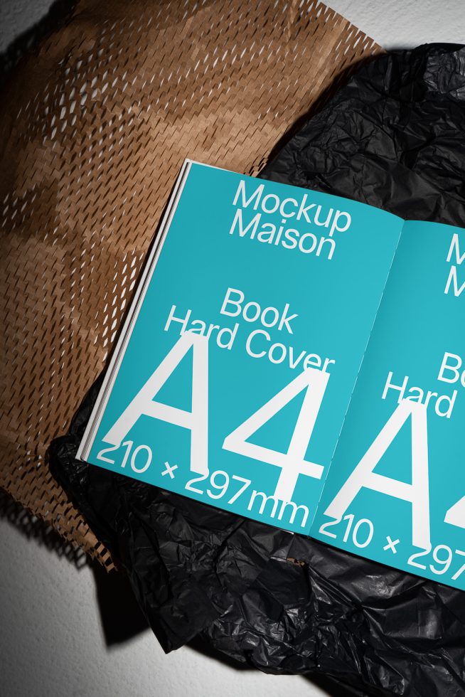 Hardcover A4 book mockup with turquoise cover, showcased on a textured brown paper and black crumpled background, ideal for designers' presentations.