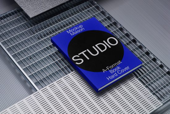 Hardcover book mockup on metallic grid surface with sleek modern design, suitable for showcasing graphics and fonts.