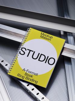 Yellow spiral-bound notebook with white circle showing Studio text on metallic surface