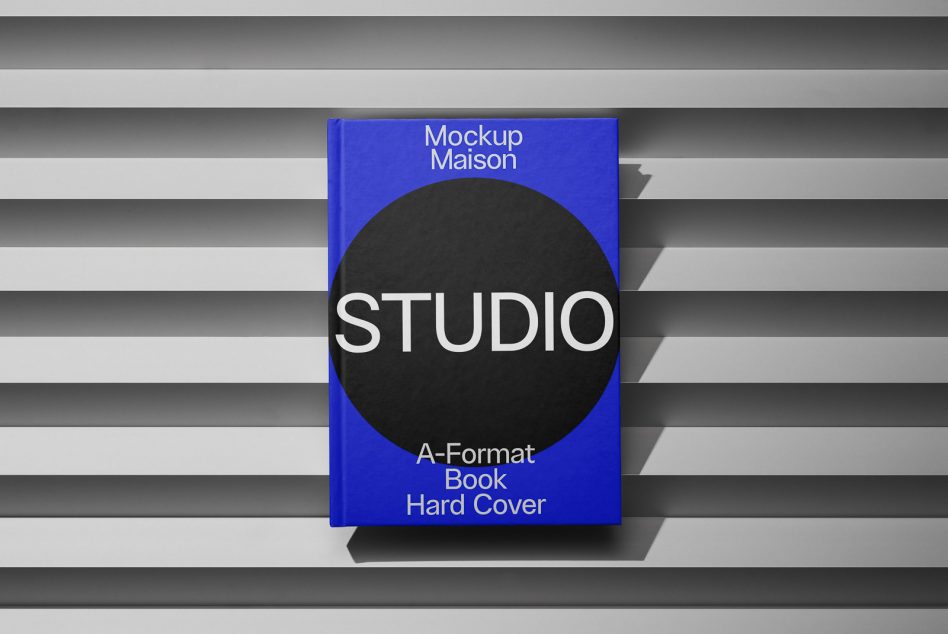 Bright blue A-format hardcover with STUDIO text on black circle, striped surface behind