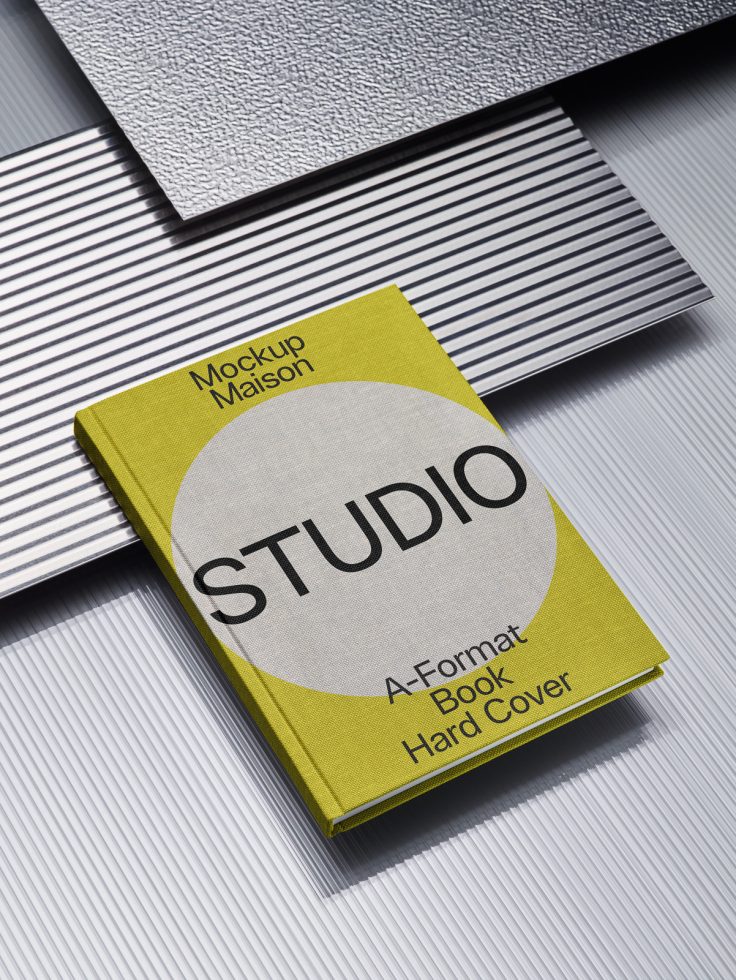 A-format hardcover book mockup with yellow cover and studio branding on striped surface for graphic design asset showcase.