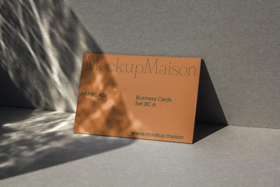 Orange business card mockup with shadows on gray surface, shows branded template