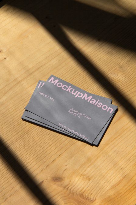 Business card mockup stack with elegant shadows on a wooden surface, perfect for presenting branding designs to clients.