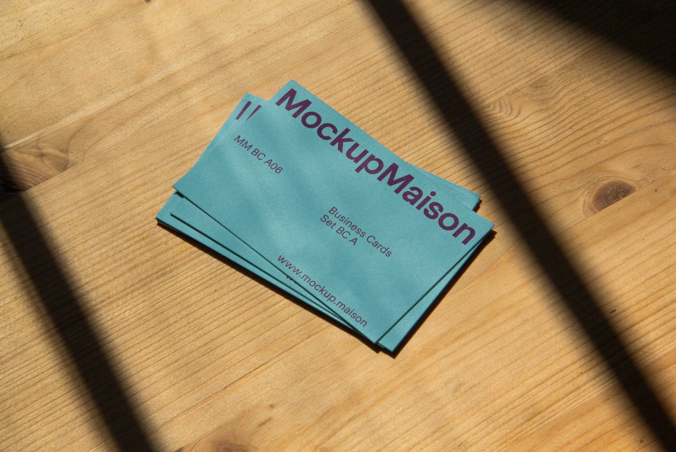 Stack of turquoise business cards on wood with natural sunlight shadow