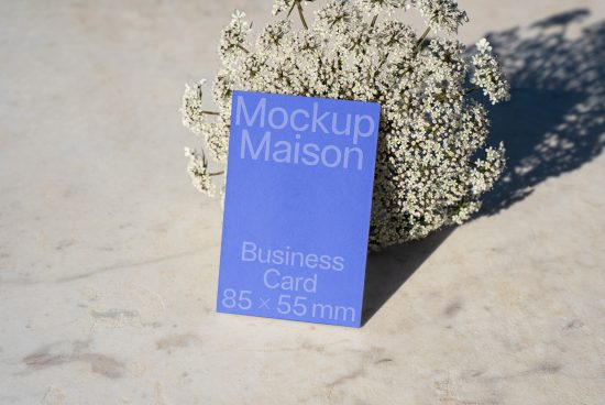 Business card mockup template with white text on blue background placed against a natural white flower bouquet, ideal for designers and branding.
