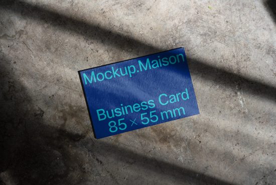 Blue business card mockup on a textured concrete surface with natural lighting and shadows suitable for professional presentation.