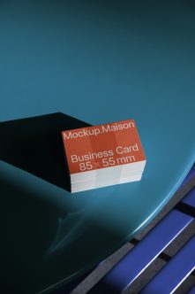 Coral business card stack on blue curved surface with geometric shapes