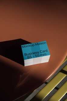 Teal business card stack on rust orange table with dramatic shadow