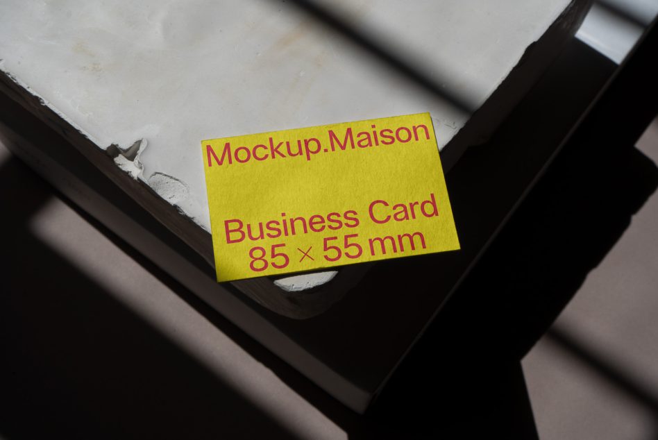 Vibrant yellow business card stack with red text on dark wood surface