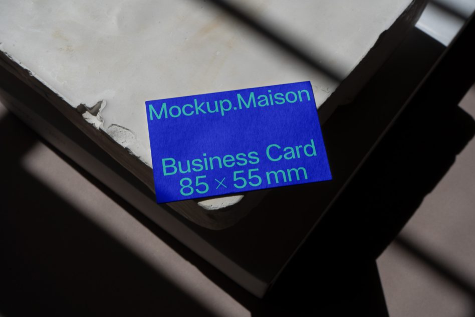 Bright blue business card stack with green text on dark wood surface