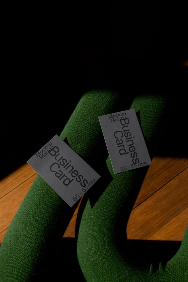 Creative business card mockup on textured green fabric with dramatic lighting, showcasing design and print options for graphic designers.