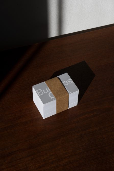 Stack of business cards with elegant design mockup on wooden surface, showcasing clean typography and shadow play, ideal for portfolio presentation.