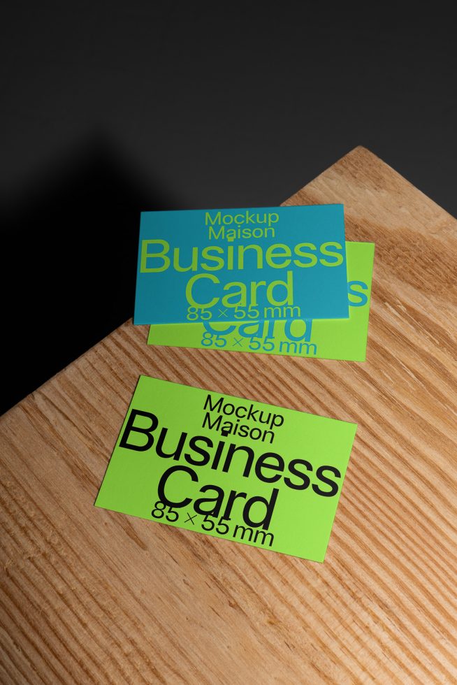 Business card mockup on a wooden surface with a contrasting dark background, showcasing front and back design, ideal for presentations and portfolios.