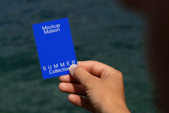 Hand holding blue card mockup with text Mockup Maison Summer Collection over water background, showcasing design for print presentation.