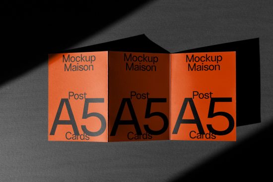 Alt: A5 postcard mockup with three standing cards in orange featuring shadow play, ideal for graphic design presentations and portfolio showcases.