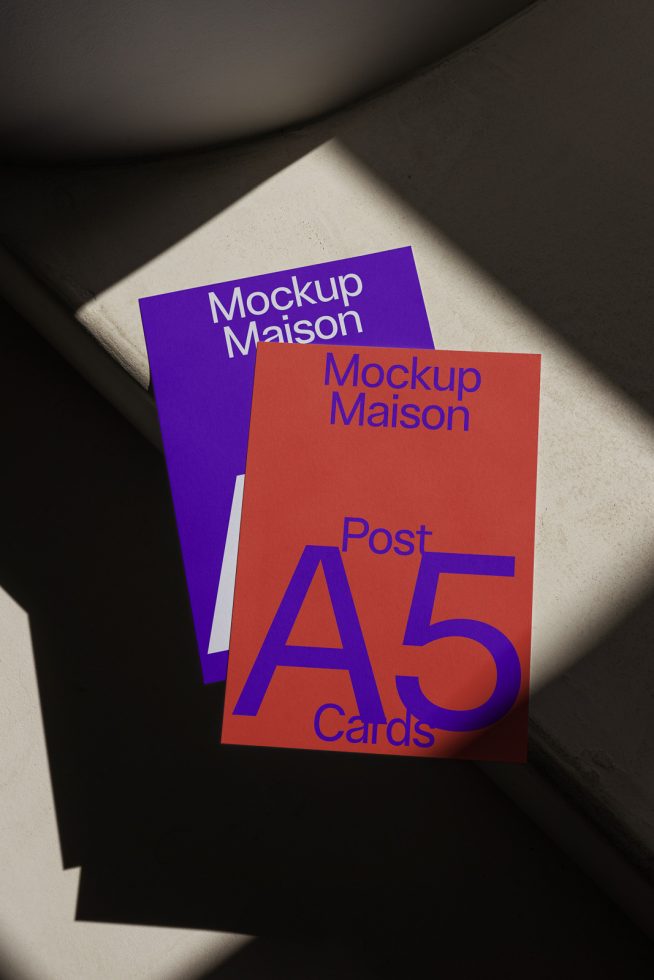 ALT: A5 postcard mockups in purple and orange with shadows, placed on a textured surface, showcasing elegant design presentation for digital asset marketplace.