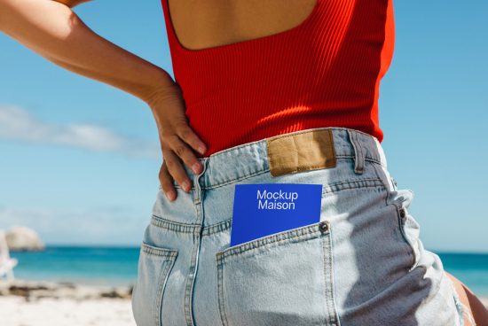 Person on beach with label mockup on jeans pocket, clear sky and sea in background, fashion mockup, denim texture, summer apparel design.
