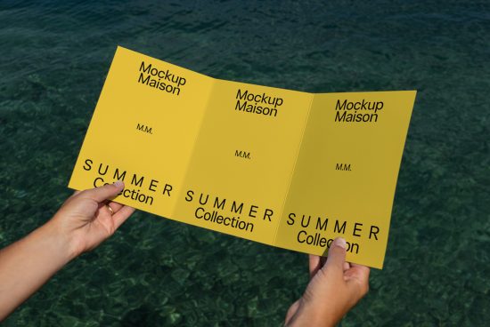 Person holding three yellow pamphlet mockups with Mockup Maison branding for a summer collection over a water backdrop, ideal for graphic design display.