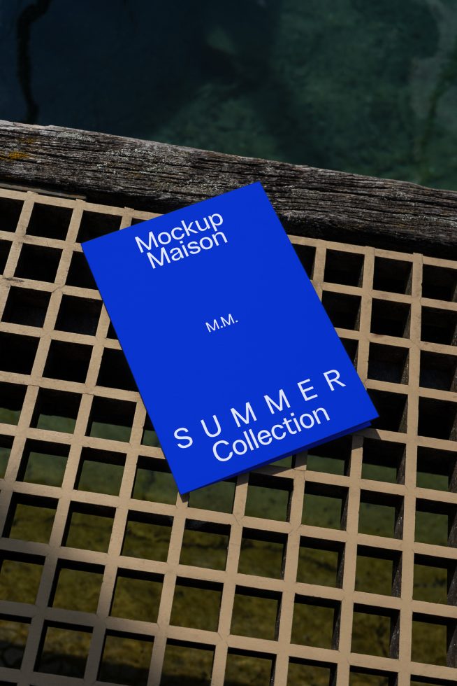 Blue magazine cover mockup lying on a textured wooden grid with water background, ideal for summer-themed graphic design projects.