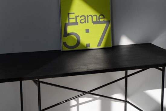 Modern poster mockup on black table against gray wall with dynamic shadows for showcasing design work and graphic presentations.
