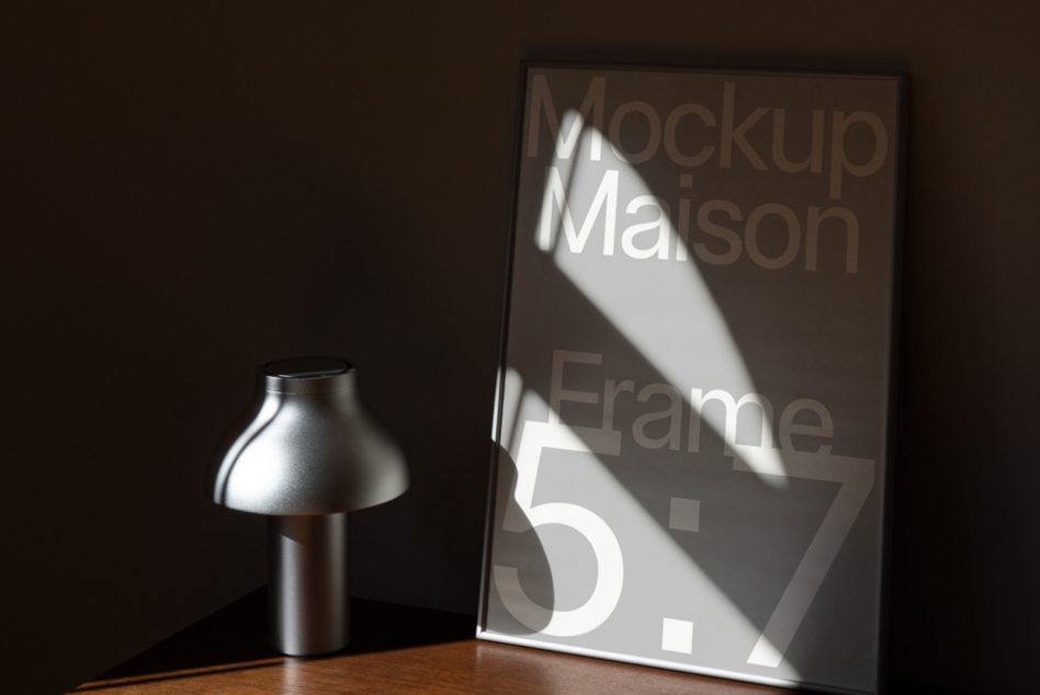 Frame mockup on wood surface with cylindrical lamp, dramatic shadow from light