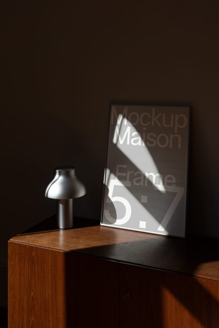 Styled frame mockup on wood furniture with metal lamp, soft window light visible