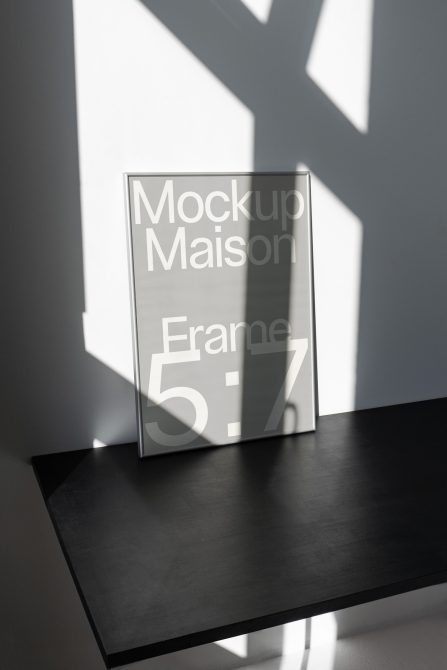 Minimalistic frame mockup on a dark table with dynamic shadows, ideal for displaying artwork in natural lighting, perfect for designers.