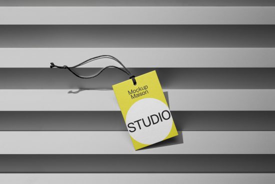 Yellow tag mockup with black cord against a striped background, ideal for branding presentations and design showcases in graphics category.