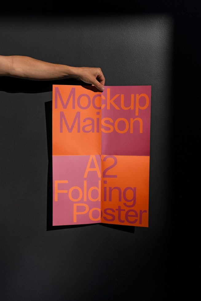 Hand holding an A2 size folded poster mockup against a dark background, showcasing design and print presentation for graphic designers.