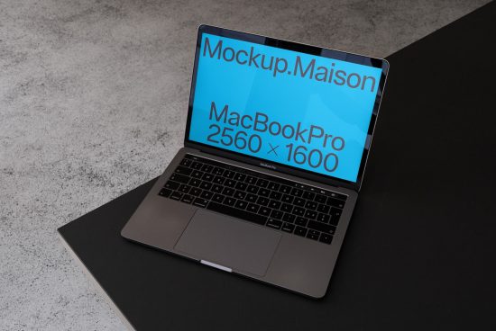Laptop mockup on gray surface showcasing screen with graphic design, ideal for presentations, digital asset for modern designers.
