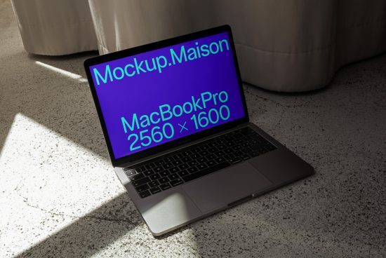 Laptop mockup on a concrete floor with sunlight casting shadows, perfect for presentations and web design showcase.