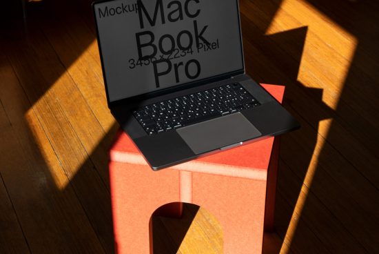 MacBook Pro laptop mockup on red stool with sunlight and shadows, ideal for digital asset designers, 3450x2234 pixels.