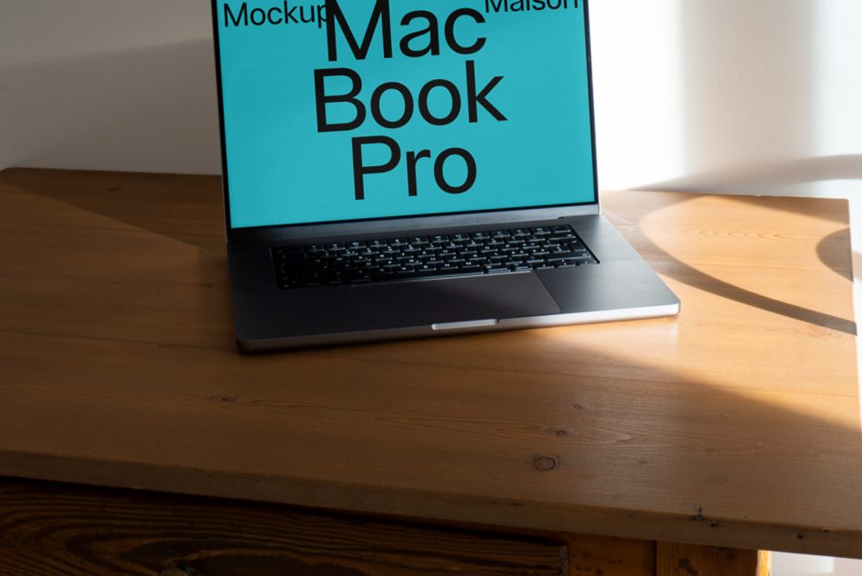 MacBook Pro on wooden desk with turquoise screen mockup, angled side view