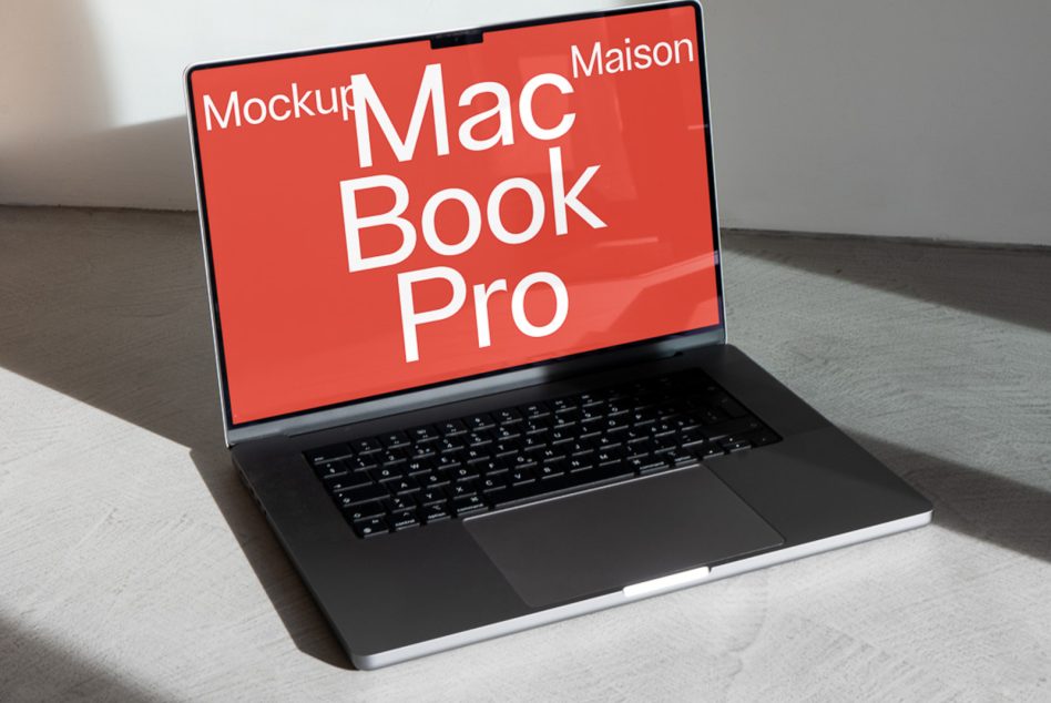 MacBook Pro on gray surface with red screen showing white text mockup