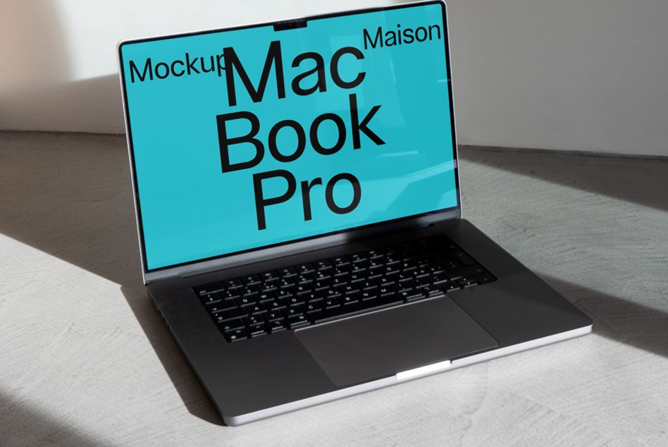 MacBook Pro on gray surface with turquoise screen showing black text