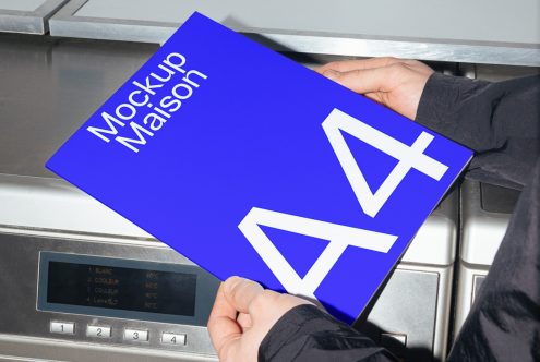 Hands holding a brochure mockup with a blue cover and geometric design in front of a metal surface, perfect for realistic presentation, print design display.