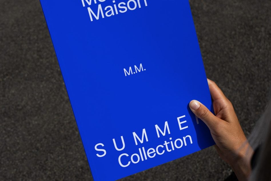 Royal blue hardcover book with white text held in hand on grey surface