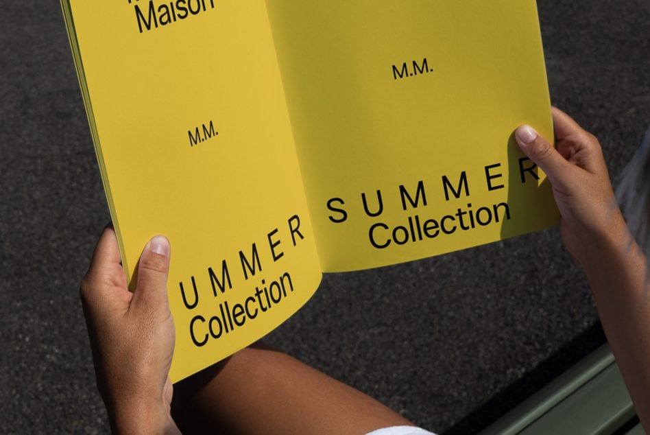 Hands holding open curved yellow bifold brochure mockup with text