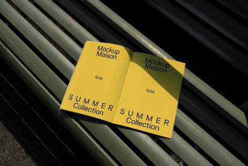 Yellow book cover mockup with elegant design on a green park bench, showcasing summer collection, perfect for graphics category on Marketplace.