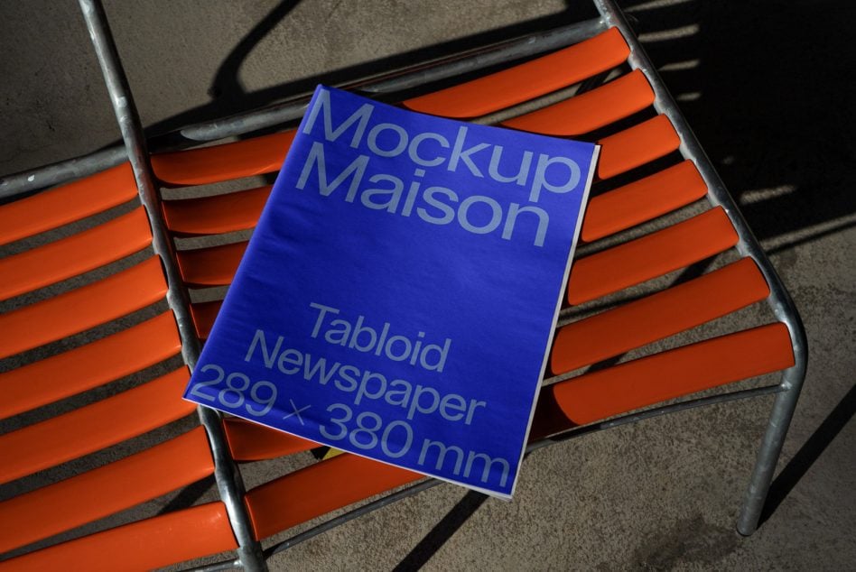 Bright blue square tabloid newspaper mockup displayed on orange metal chair slats