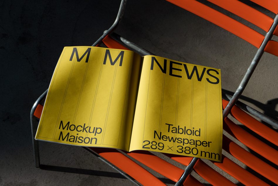 Open yellow tabloid newspaper mockup showing both pages with black text on metal chair