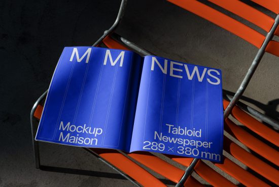 Open tabloid newspaper mockup on orange metal chair showcasing design space for graphics and fonts by designers.