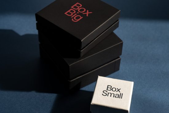 Stacked black packaging boxes with red text and a single small beige box with black text on blue background, ideal for mockup presentations.