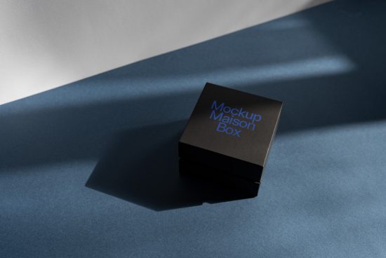 Elegant product packaging mockup of a black box with shadow on blue background, ideal for presentation and design showcase.