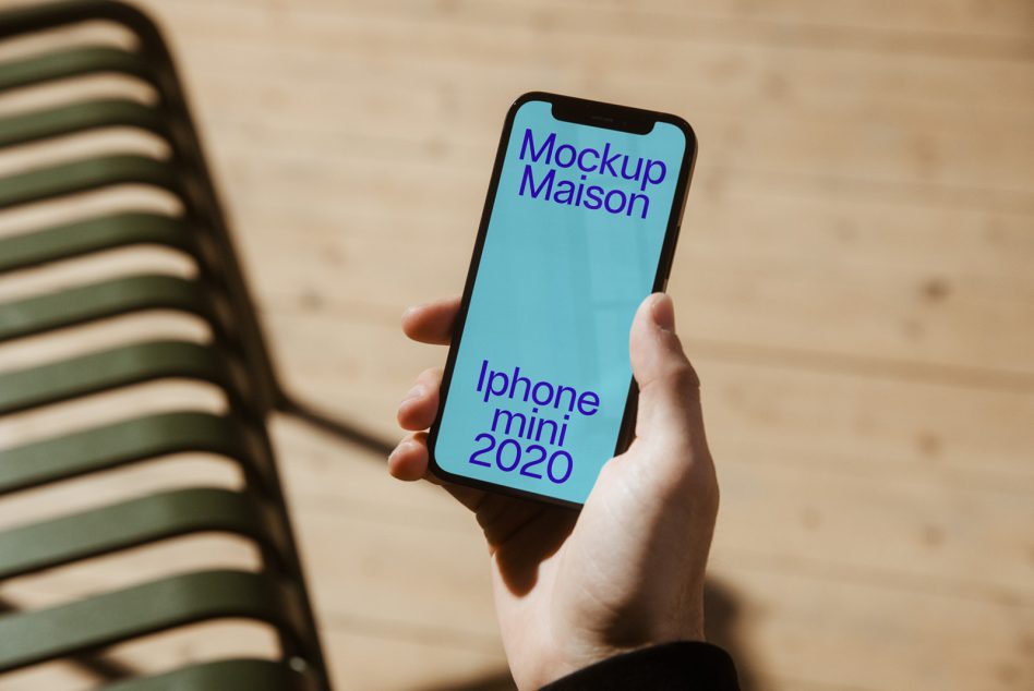 Hand holding iPhone mockup with teal screen and purple text for designers, showcasing smartphone template in a real-life setting.