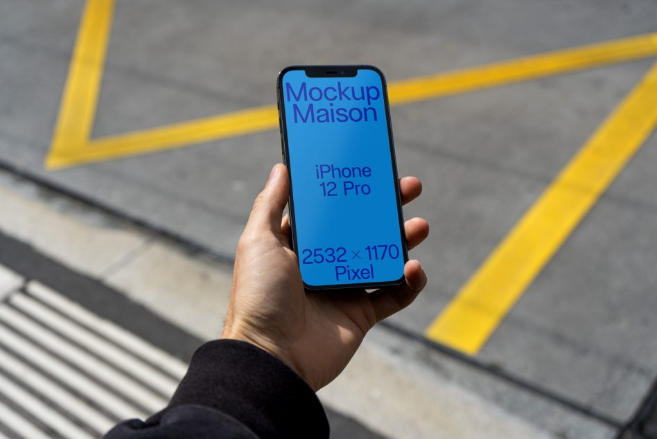 Hand holding iPhone 12 Pro mockup with street background for design presentation, realistic mobile device template 2532x1170 px.